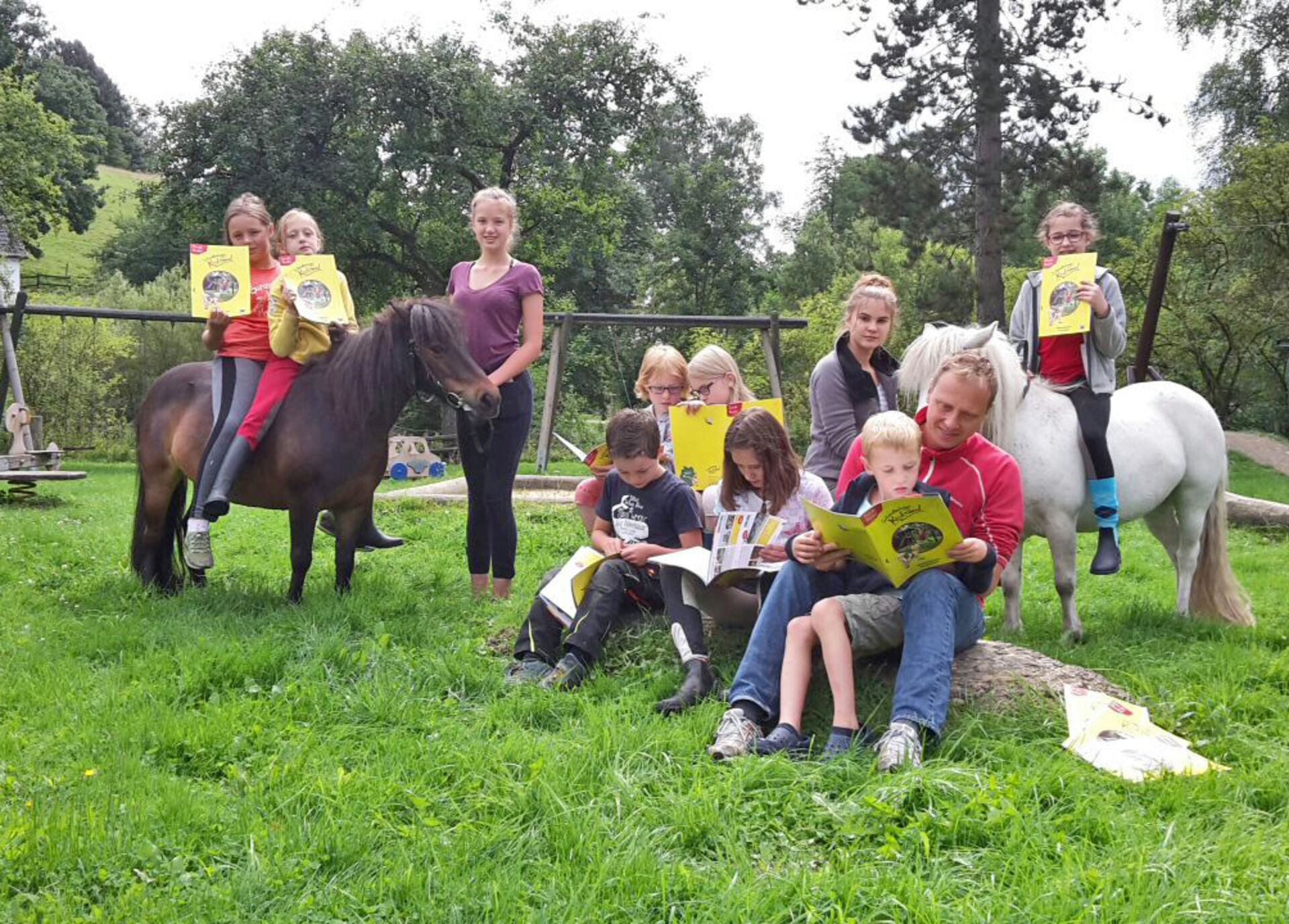 Kinder mit Ponys und dem neuen Prospekt des Schmallenberger Kinderlandes