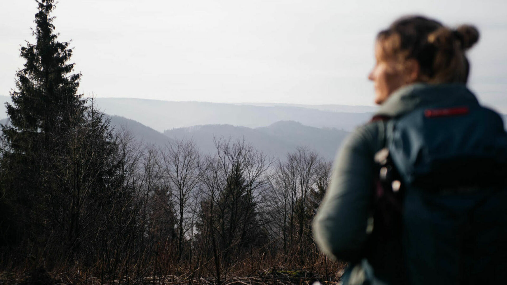 Wanderin mit Blick auf nebelverhangene Wälder
